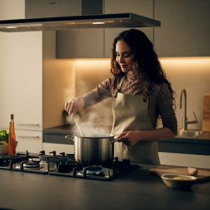 Woman at stove cooking with a steaming pot. 